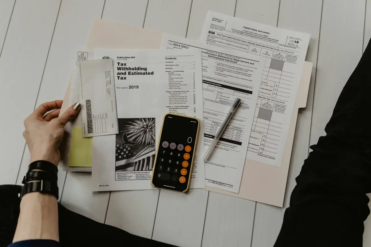 A hand holding a printed statement beside a calculator