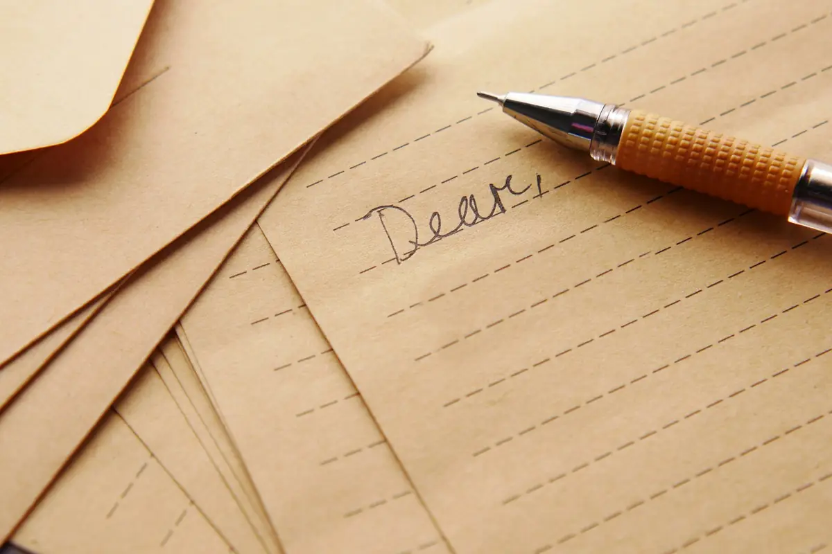 A pen resting on a letter that begins 'Dear'