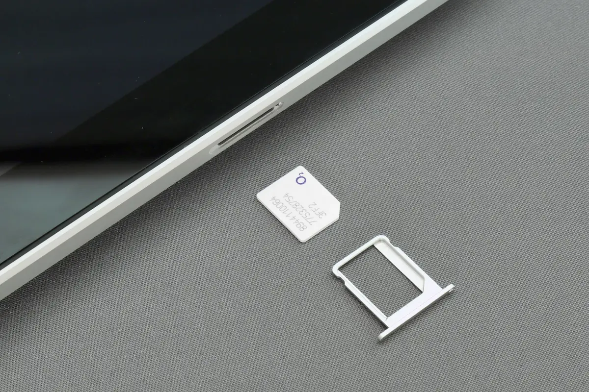 A SIM card and SIM tray beside a phone